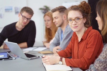 Junge Leute sitzen an einem Tisch gemeinsam vor einem Laptop
