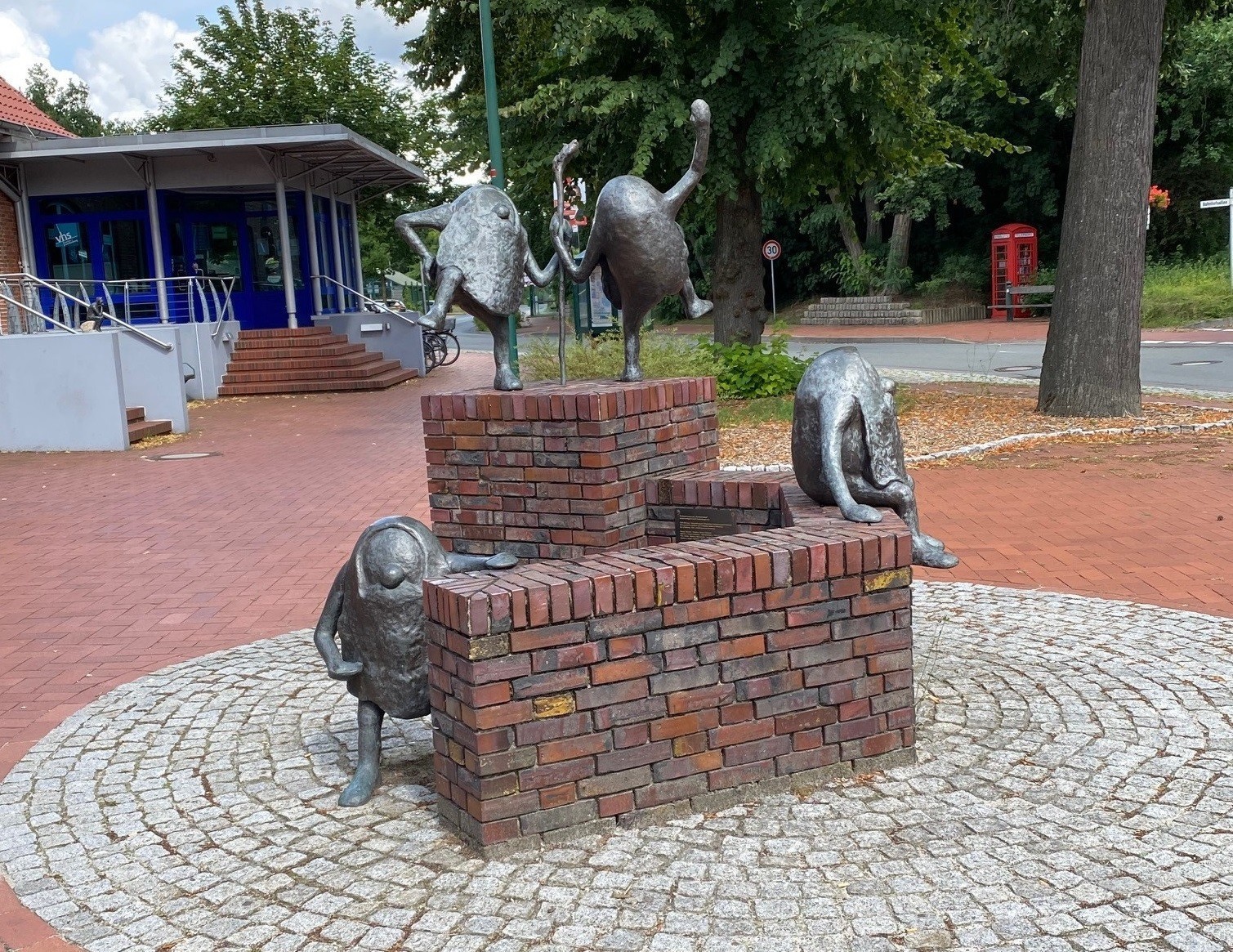 Osenzwerge tanzen und sitzen auf einer Mauer vor dem Bahnhof in Sandkrug