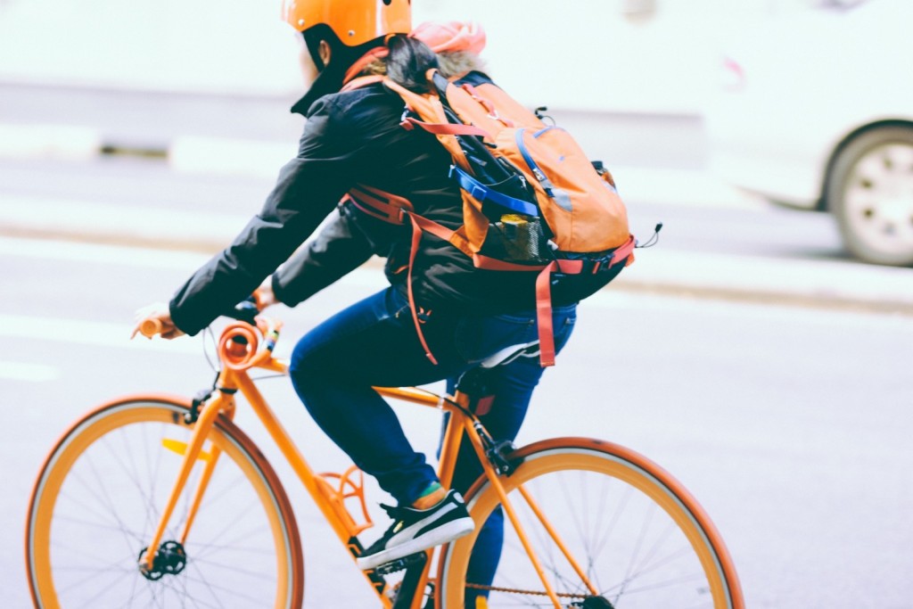 Fahrradfahrer mit Helm und Rucksack auf orangenem Fahrrad